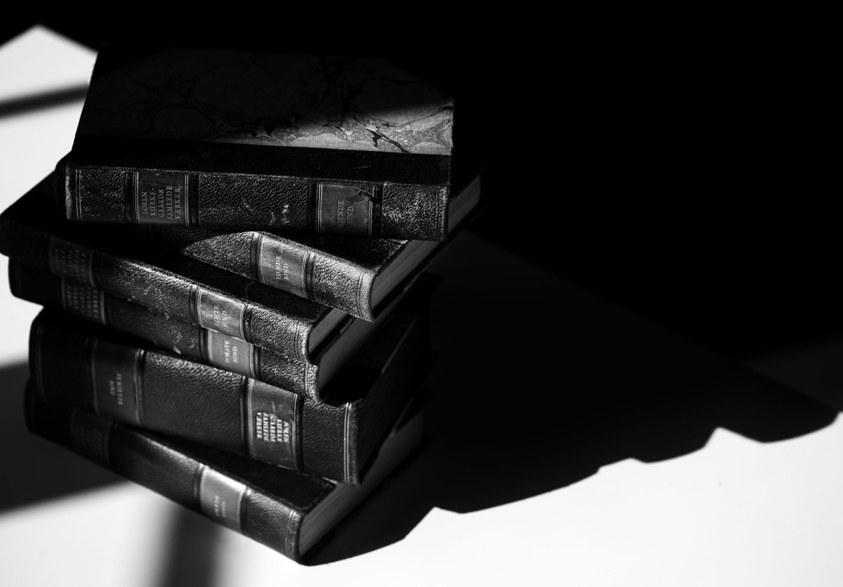 Pile of old book volumes of the collected works of Kierkegaard. Dramatic photo in black and white.